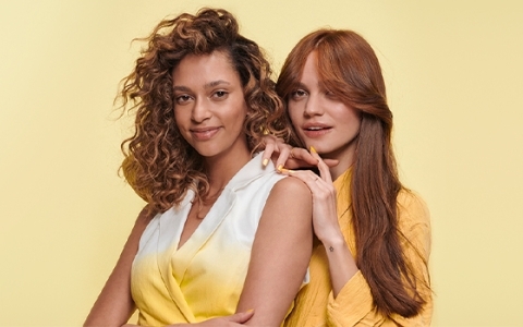 Two women in yellowish clothes on a yellow background