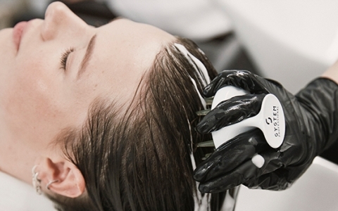 Stylist washes a woman's head at the sink using a System Professional brush